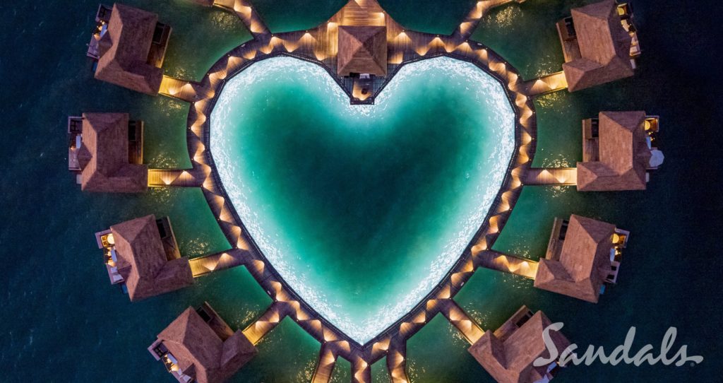 Aerial view of heart-shaped overwater bungalows at a Sandals resort