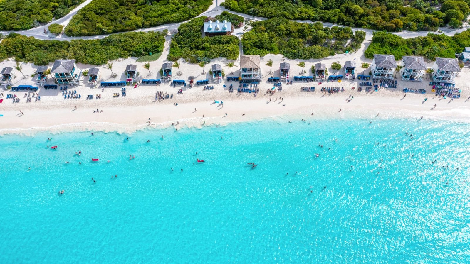 Aerial view of the main beach at RelaxAway, Half Moon Cay, Holland America Line's private island in the Bahamas, with blue loungers, beach cabanas and swimmers in turquoise water